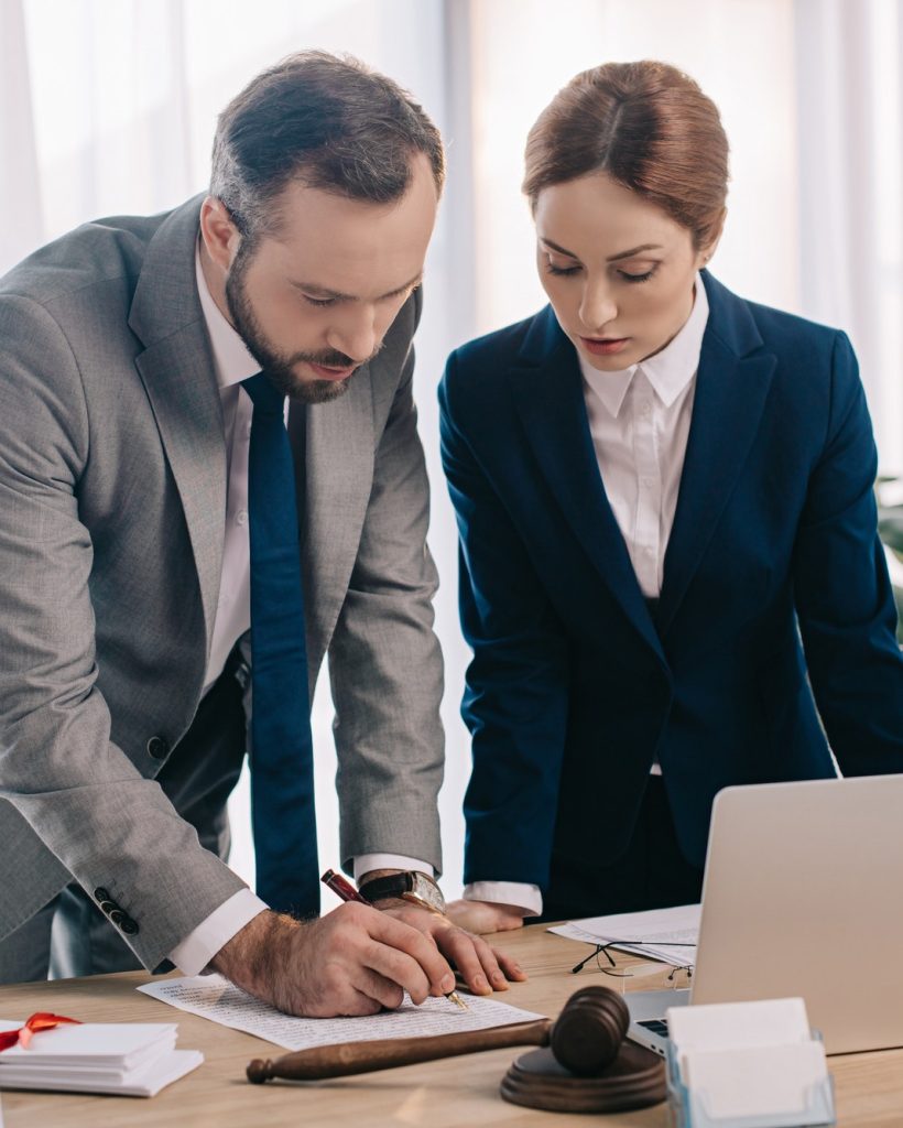 lawyers-in-suits-working-together-on-project-at-workplace-with-gavel-and-laptop-in-office.jpg